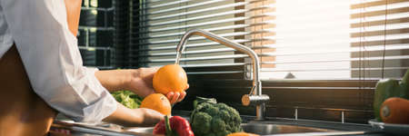 Asian hands woman washing fruit orange and preparation healthy food in kitchen.の写真素材