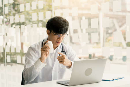 Asian doctor provides online counseling to patients during the virus outbreak keeping a social...