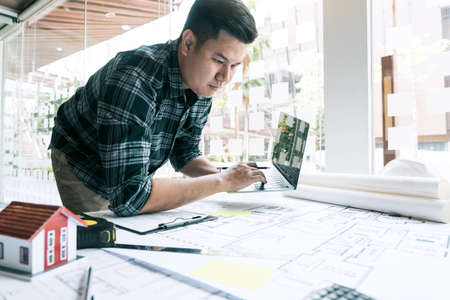 Architect working new project and using laptop with in office.