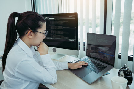 Asian female software developer is worried about analyzing code-based systems at his office.