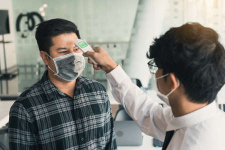 Employees are measuring their colleagues' temperatures during the outbreak of the virus.の写真素材