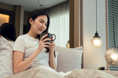 Asian woman holding a cup of coffee in the morning after waking up.の写真素材