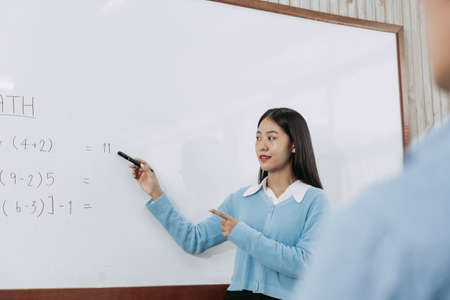 Young asian teacher teaching students at classroom.の写真素材