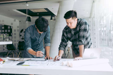 Architects or engineering working with blueprints and discussing project together at the meeting in...