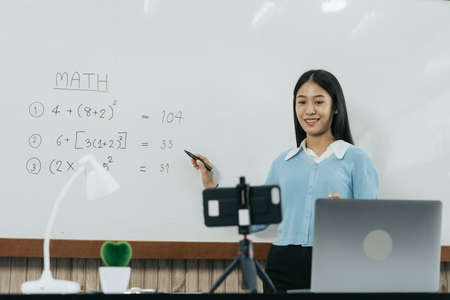 Teacher explaining the numbers on the board while video calling with students studying online.の写真素材