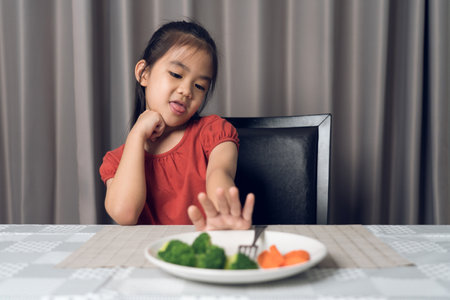 Little cute kid girl refusing to eat healthy vegetables. Children do not like to eat vegetables.の写真素材