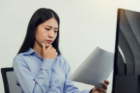 Concentrated asian woman brainstorming while coding data on desktop PC while working on computer codes in the office.の写真素材