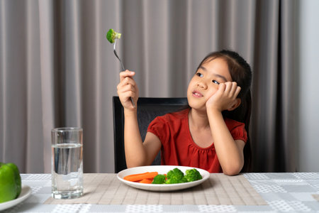 Little cute kid girl refusing to eat healthy vegetables. Children do not like to eat vegetables.の写真素材