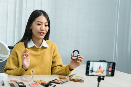Asian teenage girls doing makeup vlogs and using a video mobile camera to record vlogs and publish them online at home.の写真素材