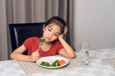 Little cute kid girl refusing to eat healthy vegetables. Children do not like to eat vegetables.の写真素材