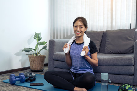 Asian women wiping their sweat away after exercising at home.