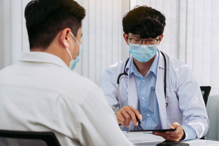 Doctors are explaining the treatment of a sick patient in tablets while wearing a mask during the virus outbreak.の写真素材