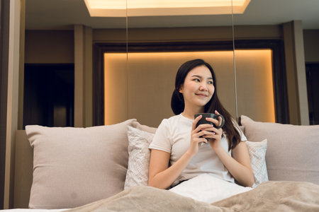 Asian woman holding a cup of coffee in the morning after waking up.の写真素材