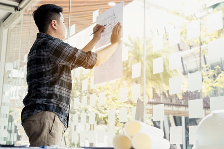 Interior designer or architect reviewing blueprints and holding pencil drawing on desk at home office.の写真素材
