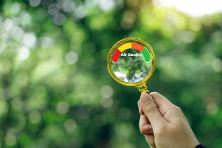 Hand holding a magnifying glass to check the good air quality and clean outdoor air quality safe.