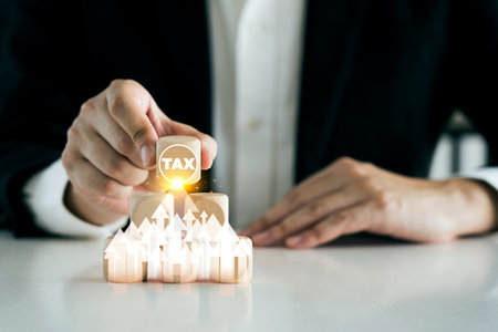 Businessman's hands holding a wooden cube with tax symbol in increased tax concept.の写真素材