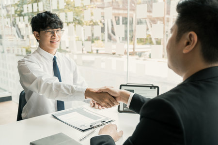 Manager and employee interview concept with handshake after talking about contract signing.の写真素材