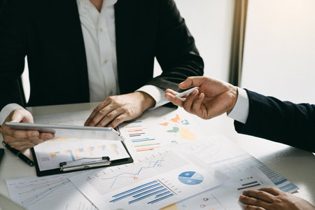 Business partnership coworkers using a tablet to analysis graph company financial budget report and cost work progress and planning for future in office room.の写真素材