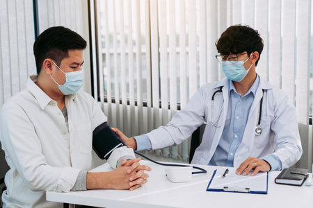 Doctor checking a senior patient blood pressure in office room.の写真素材