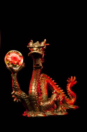 Chinese Dragon holding a Chrysanthemum Sphere with red highlights, isolated on black backgroundの写真素材