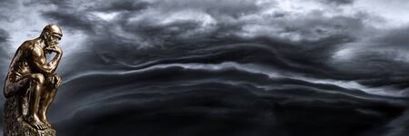 A bronze replica statue of Rodin's Thinker on a smoky backgroundの写真素材