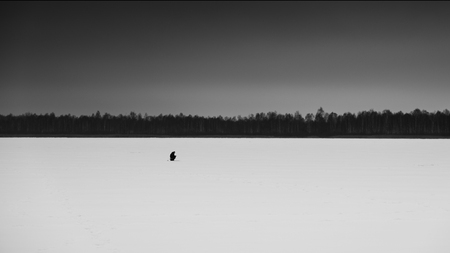 A lone fisherman on a frozen winter lake. Winter fishing.の写真素材
