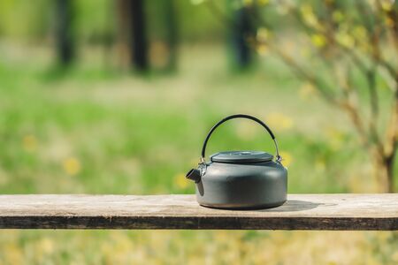 Kettle standing on a wooden bench.の写真素材