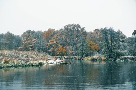 The first snow falls on the autumn riverの写真素材