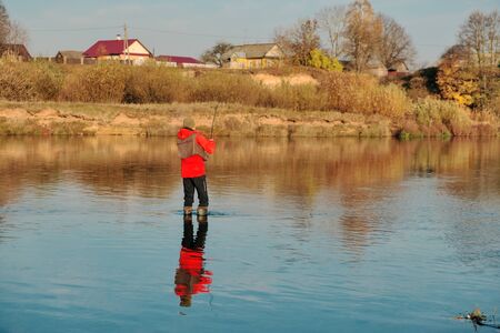 A fisherman is standing in boots and fishing.の写真素材