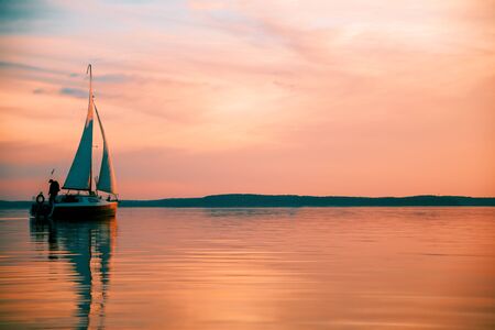 Sailing boat floats on the lake at sunset.の写真素材
