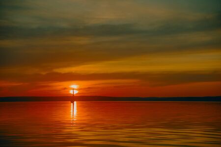 Sailing boat floats on the lake at sunset.の写真素材