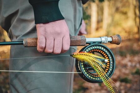 Fisherman holds fly fishing rodの写真素材