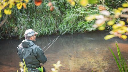 A fisherman catches spinning in the waders. Trout fishing.の写真素材