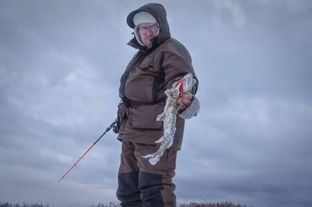 Fisherman caught a pike on winter fishing.の写真素材