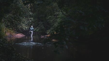 The fisherman moves along a beautiful stream. Trout fishing.の写真素材