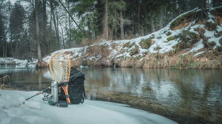 Fishing gear on the shore of a winter creek.の写真素材