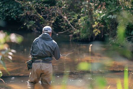 A fisherman casts a bait spinning on the background of a beautiful river.の写真素材