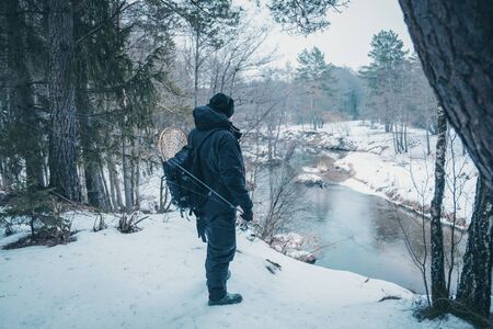 Fisherman with rod on the river bank.