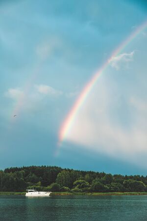 The yacht sails on the forest lake on the background of a rainbow.の写真素材
