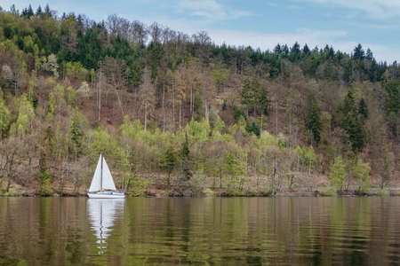 Sailing boat on a lake on the background of a spring forest.の写真素材