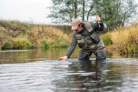 Happy fisherman pulls a fish.の写真素材