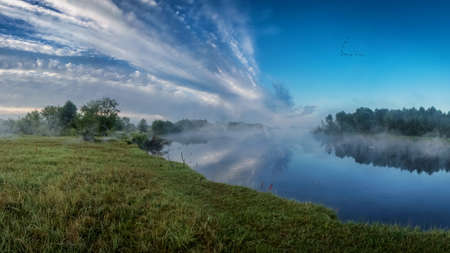 Evening on the river. Fog over the river on a background of blue sky and beautiful clouds.の写真素材