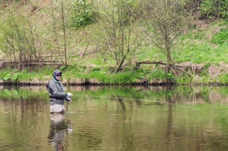 Fisherman fishing on a small spring river. Fly fishing.の写真素材