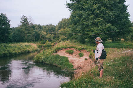 Fly fishing. Fisherman makes a cast on a beautiful forest stream.の写真素材