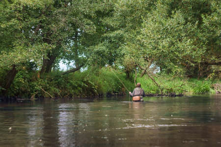 Fisherman catches a fly on the beautiful forest river.の写真素材