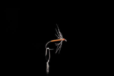 Handmade fishing fly close-up on a dark background.の写真素材