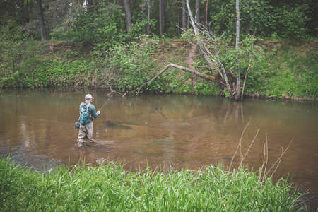 The fisherman catches with a spinning rod on the river.の写真素材