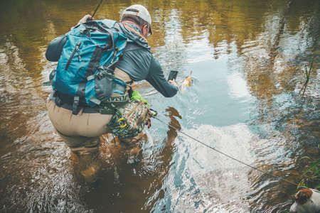 An angler photographs the trout he has caught.の写真素材