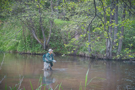 The fisherman catches with a spinning rod on the river.の写真素材