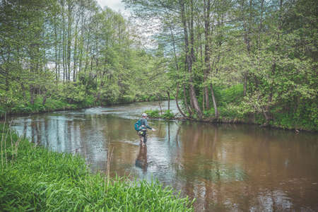 The fisherman catches with a spinning rod on the river.の写真素材